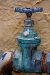 Close-up of the old rusty grunge steel pipe valve for water supply that stays at the outside of residence building.

