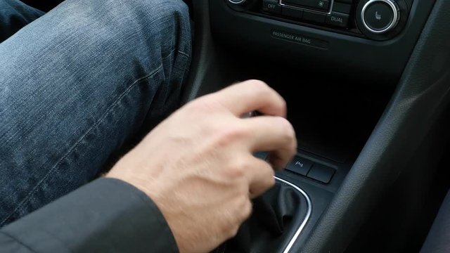 man is shifting gears in a car