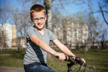 Cheerful smiling boy and bike in city park.