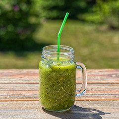 Healthy Vegan Green Smoothie With Spinach, apple, celery, kiwi, Brussels sprout, avocado, in glass, outdoor, on nature background.