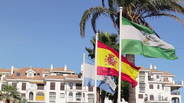 Flag Of Spain, Andalusia and Malaga waving in the wind  in famous Bay "Puerto de la Duquesa" Manilva - Malaga- Spain Costa del sol 