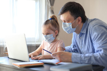 Father and child at home doing online school teaching class. Distance learning in epidemic of COVID-19.