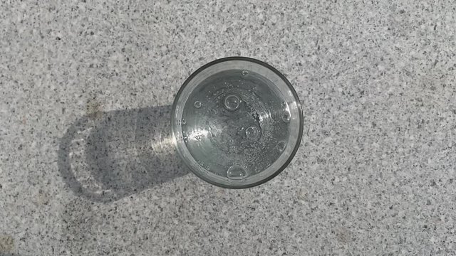 Topview on a glass full of sparkling mineral water and soda on a table in the sun in the garden