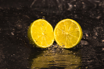 lemon, laim, slices, drops of water on a black background
