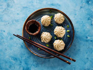 Chinese steamed dumplings in a plate with soy sauce and chopsticks top view