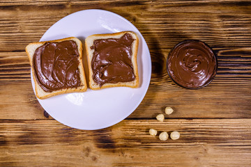 Two sandwiches with chocolate spread on a white plate. Top view
