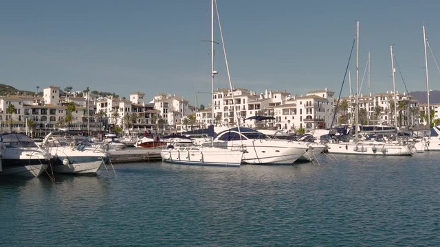 Beautiful panoramic view of "Puerto de la Duquesa" Yachts and boats docked in the Harbour. Luxury Apartment Urbanisation and Restaurants. Camera Pan Left
