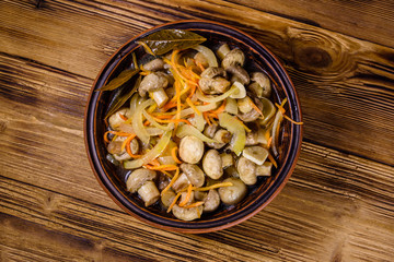 Canned mushrooms with carrot and onion in a ceramic bowl. Top view