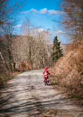 Five year old girl rides a pink bike in a forest in the mountains of German Harz