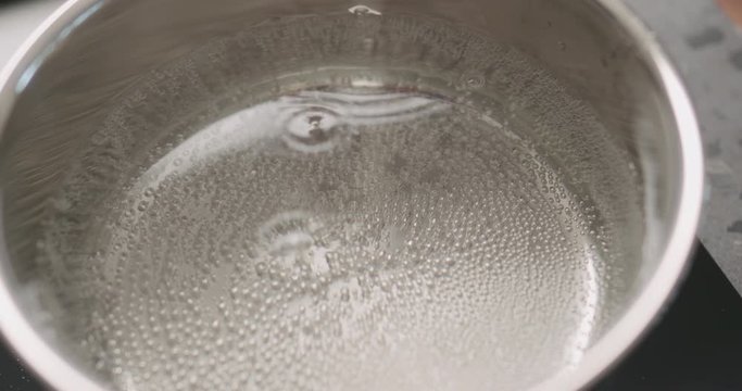 Slow motion handheld hot water in pot before boiling