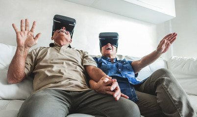 Senior mature couple having fun with virtual reality glasses - Old people using new headset goggles trends technology - Joyful elderly lifestyle concept - Focus on center hands