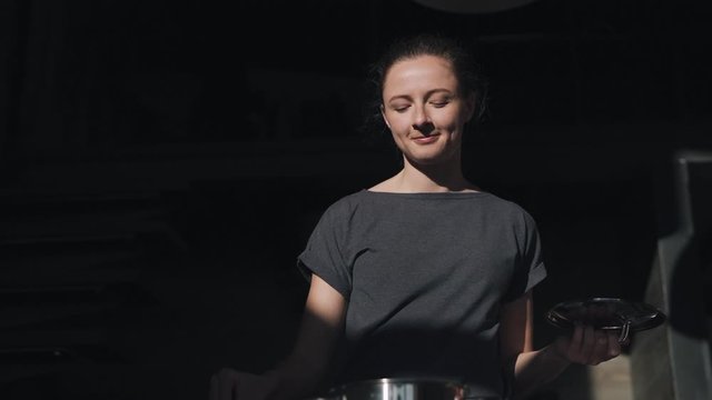 Young happy and beautiful woman in kitchen holding cooking pot excited and satisfied preparing soup delighted tasting delicious