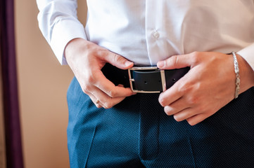 Groom holding hands on belt