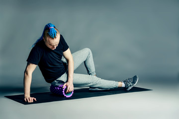 Portrait of a young man with an unusual hairstyle of mohawk from blue braids in sportswear doing...