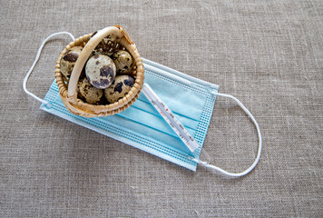 Easter Holiday with wooden basket, quail eggs with medical mask and thermometer on rustic textured...