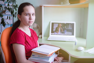 Teen girl sitting at a table with a laptop.