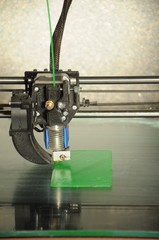 close-up 3D printer head, printing plate made of green plastic 