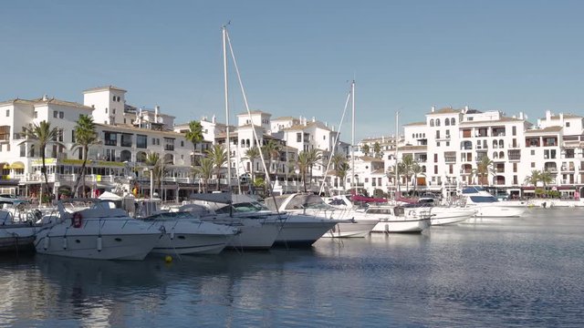 MANILVA, MALAGA / Spain - December 14 2019: Beautiful panoramic view of "Puerto de la Duquesa" Yachts and boats docked in the Harbour. Luxury Apartment Urbanisation and Restaurants. Camera Pan Left
