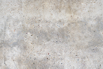 Old stained concrete wall with multi-colored pebble stones. Texture of gray color cement background, dry scratched surface wall cover sand, shabby detail.