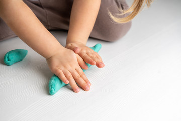 Obraz na płótnie Canvas Closeup hands of preschooler child roll out dough for modeling. quarantined children's art
