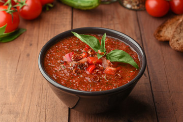 Vegetarian organic soup gazpacho on wooden background. Cold summer tomatoes soup with pepper, bread croutons cucumber and basil. Copy space on Wood background.