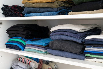 neatly stacked and folded colorful men's clothes in a closet