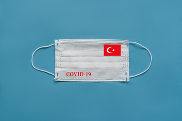 Medical mask with the flag of Turkey and the inscription COVID-19 on a blue background