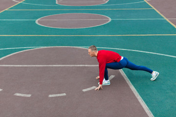 Obraz premium Photo of a man man flexes his leg muscles on the sports ground before running.