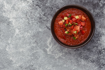A bowl of tomato gazpacho soup. Copy space. Stone gray background. Top view of spicy gazpacho soup. Gazpacho from above. 