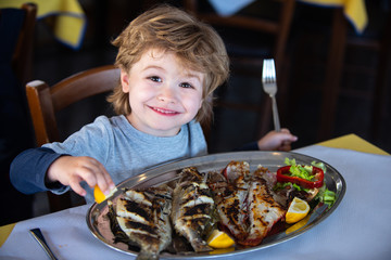Happy smile. Healthy eating for children. Grilled fish for a healthy dinner. Boy smiles in a restaurant.