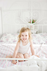 Obraz na płótnie Canvas girl laughs sitting on bed in parents bedroom.