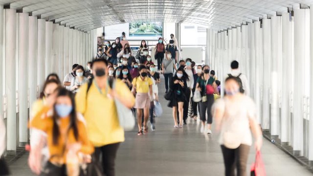 4K time-lapse of crowded Asian people wear face mask, walk in pedestrian walkway. Coronavirus disease Covid-19 pandemic outbreak, social distancing, city life or PM 2.5 air pollution concept, zoom out