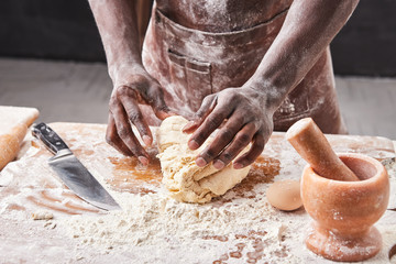 Dark skin baker man kneads Dough in the kitchen. Pastry chef prepares yeast dough for pizza pasta.