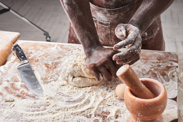 Dark skin baker man kneads Dough in the kitchen. Pastry chef prepares yeast dough for pizza pasta.