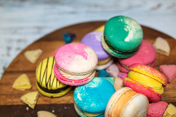 a beautiful colored macaroon lying disorderly on a cutting board.