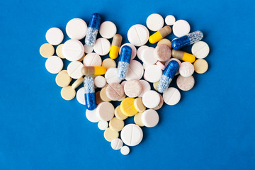 Heap of pills, tablets, capsules on blue background. Drug prescription for treatment medication health care concept wth copy space.