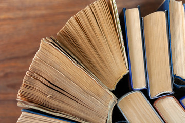 Naklejka premium Old and well used hardback books or text books in a book shop or library. Many Books Piles. Hardback books on wooden table top view. Back to school background with copy space.