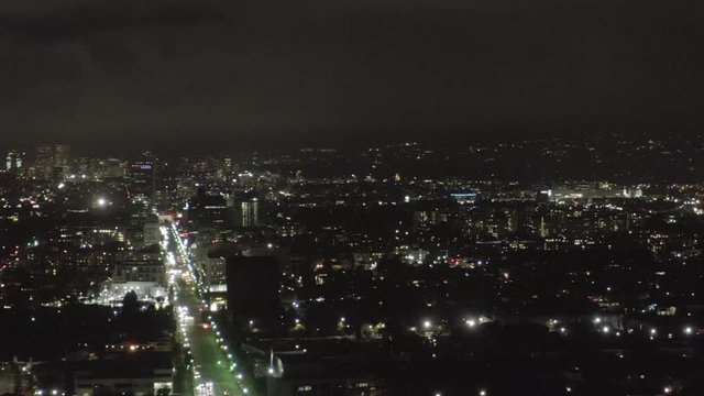 AERIAL: Over Dark Hollywood Los Angeles at Night view on Wilshire Blvd with Clouds over Downtown and City Lights 