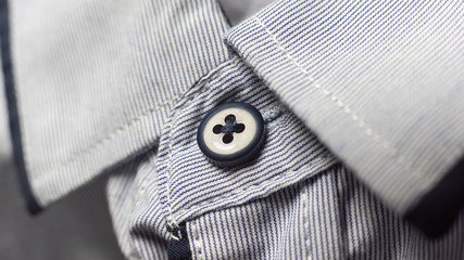 Black button of light shirt collar. background of a white shirt