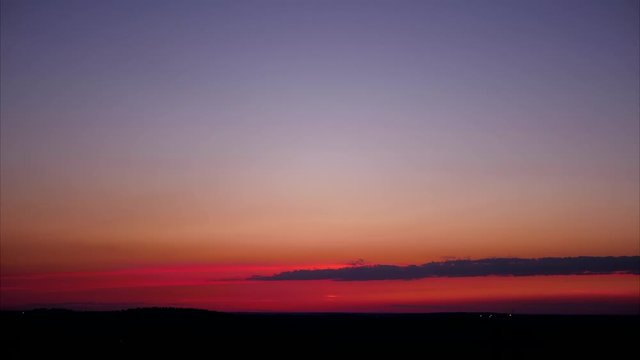 aerial panoramic time lapse of pink and violet twilight sky with long cloud moving over horizon in 4k