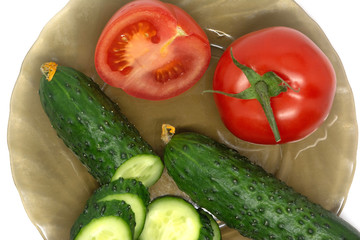 green fresh sliced cucumber and tomato on glass plate