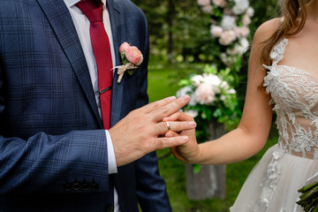 The bride puts the ring on the finger of groom