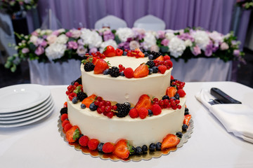 A large wedding cake decorated with strawberries. In the background is wedding decor