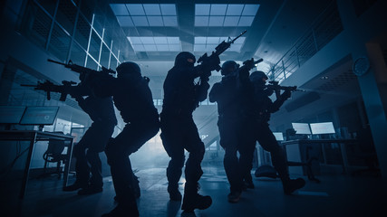 Masked Team of Armed SWAT Police Officers Move in a Hall of a Dark Seized Office Building with Desks and Computers. Soldiers with Rifles and Flashlights Surveil and Cover Surroundings.