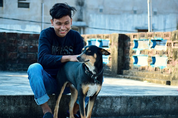 a teenager boy and a black indian dog playing outdoor enjoying friendship partner
