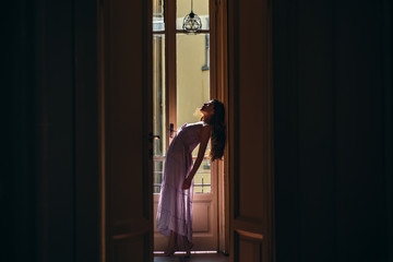 Woman meets morning near balcony. She happy dances. Girl is dressed in nightwear. Young woman standing near balcony. Relaxation and comfort moment day off.