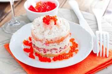 Holiday salad with red fish, shrimp, crab sticks, vegetables and red caviar, selective focus