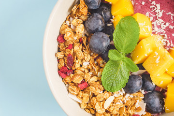 Handmade Bowl healthy tasty breakfast of yogurt, smoothie with granola, nuts, mango and berries.