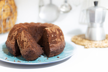 Fototapeta na wymiar Chocolate cake with thread shape on white background with defocused kitchen objects background