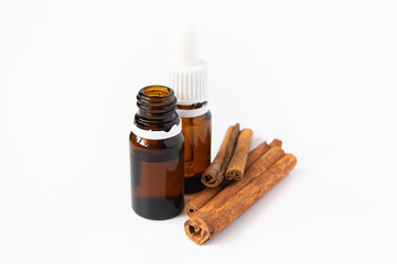 natural cosmetics concept, composition of glass bottles with oil and cinnamon sticks on a white...